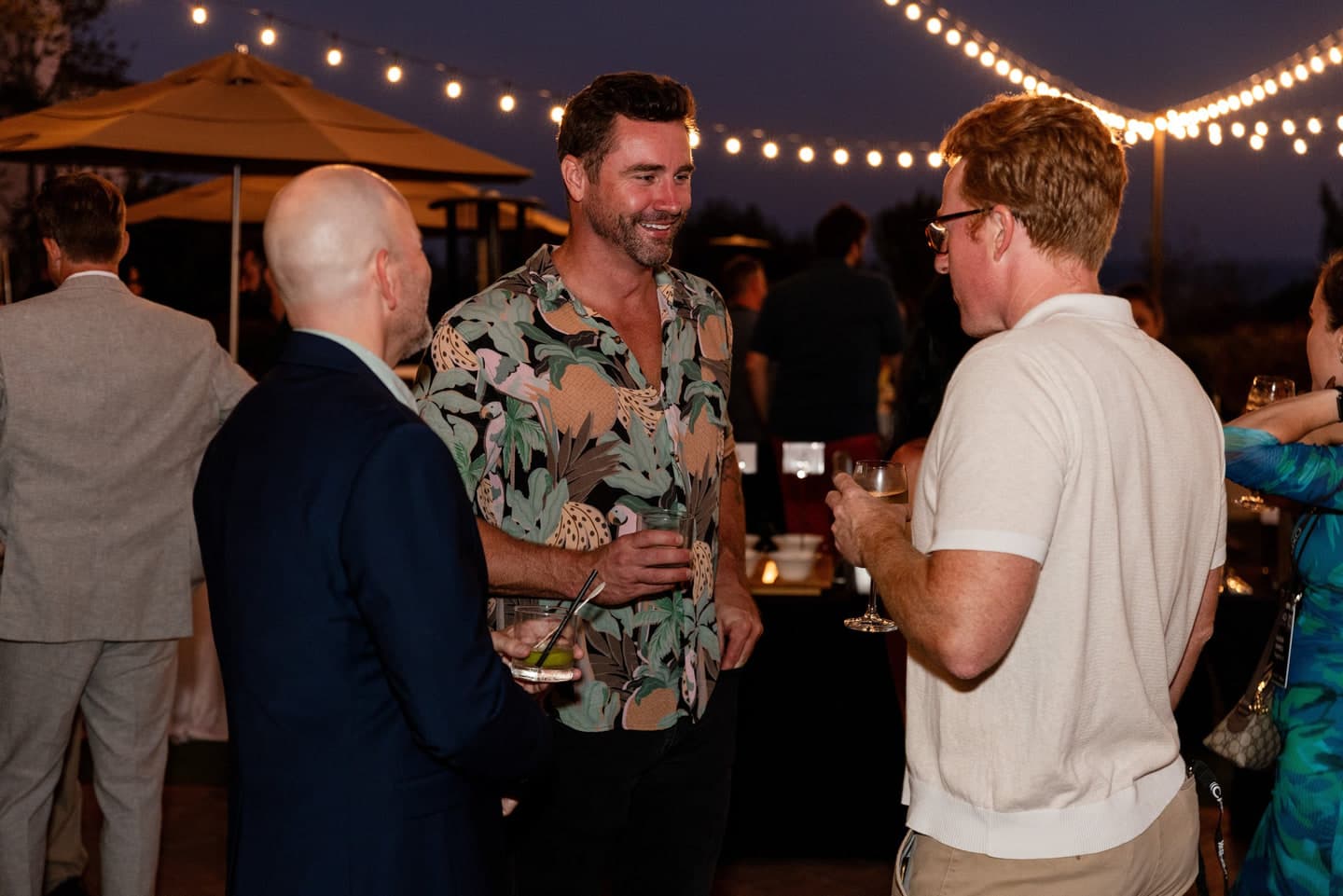 Attendees talking under string lights on the rooftop